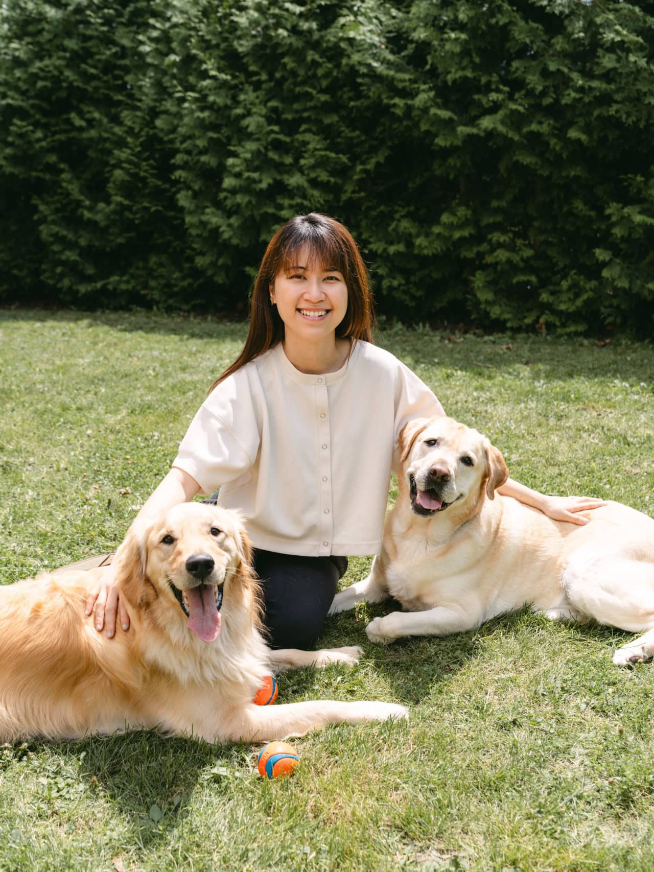 Kathy sitting on the grass with two of her dogs