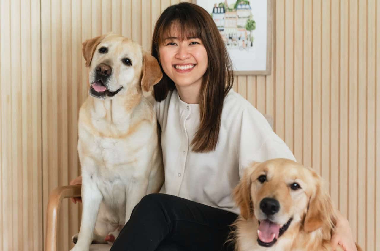 Kathy hugging her two dogs: Horlick and Bagel.